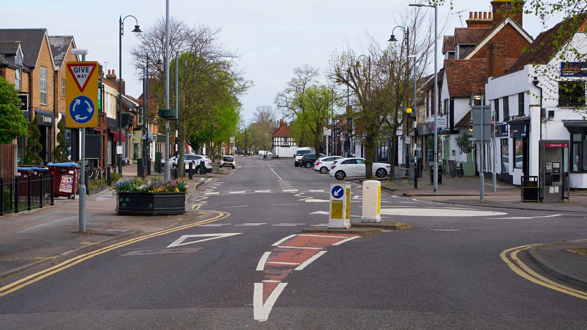 A quiet street scene in England featuring road signs and parked cars, a typical town view.