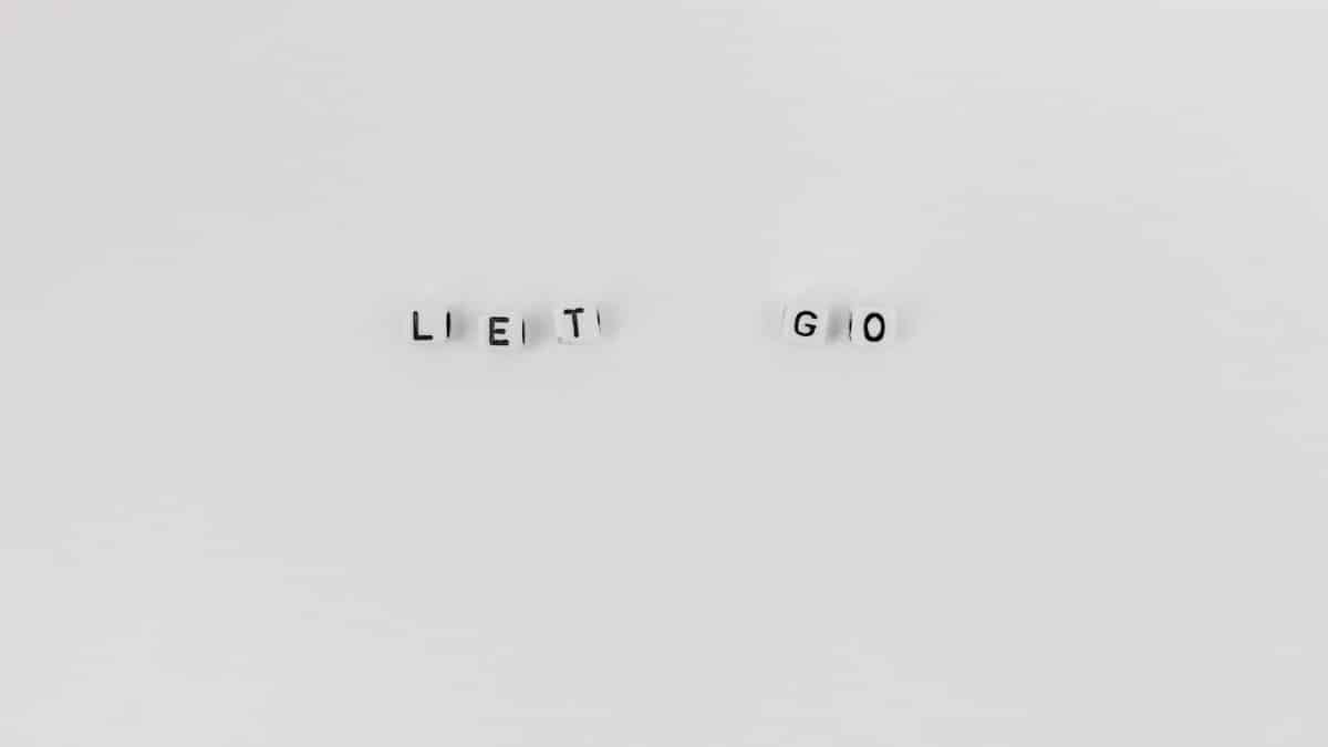 Minimalist composition featuring 'Let Go' spelled with letter dice on a clean white background.