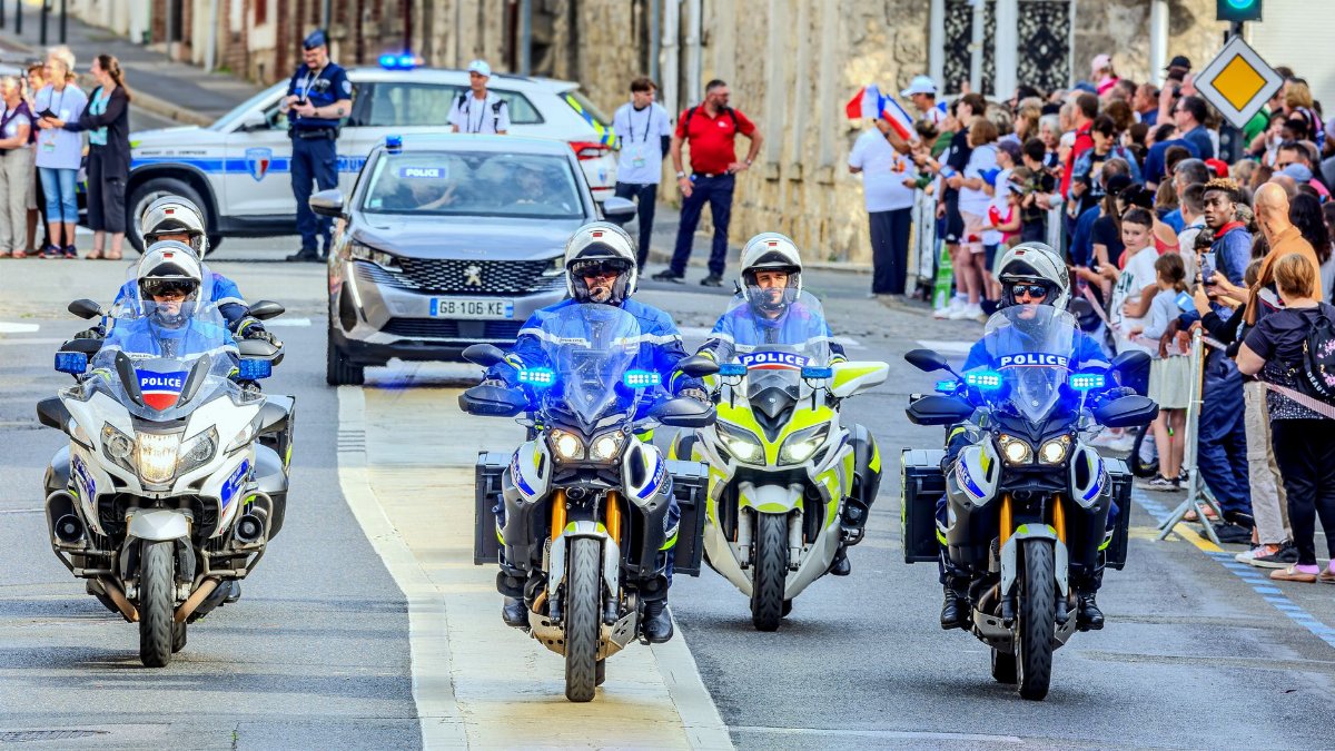 Police motorcade escorting people during a city event with vibrant crowd and motorcycles.