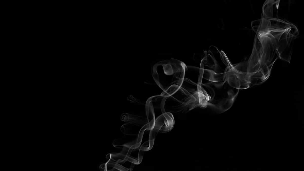 Abstract black and white image of swirling smoke patterns against a dark backdrop.