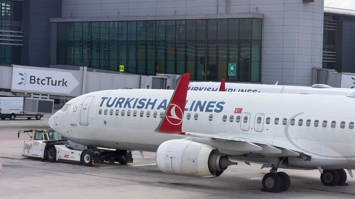 Turkish Airlines plane preparing for departure at Istanbul Airport, parked at a terminal gate.