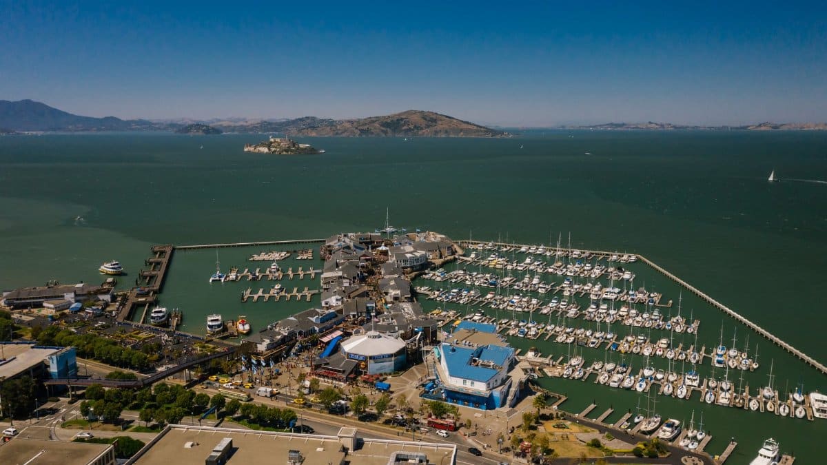 Drone shot of San Francisco marina with Alcatraz Island in the background on a sunny day.