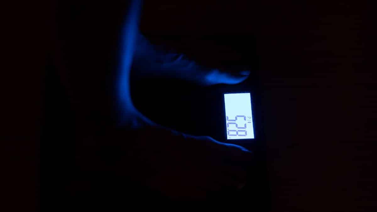 Close-up of a digital weighing scale displaying weight in a dark room with blue illumination.