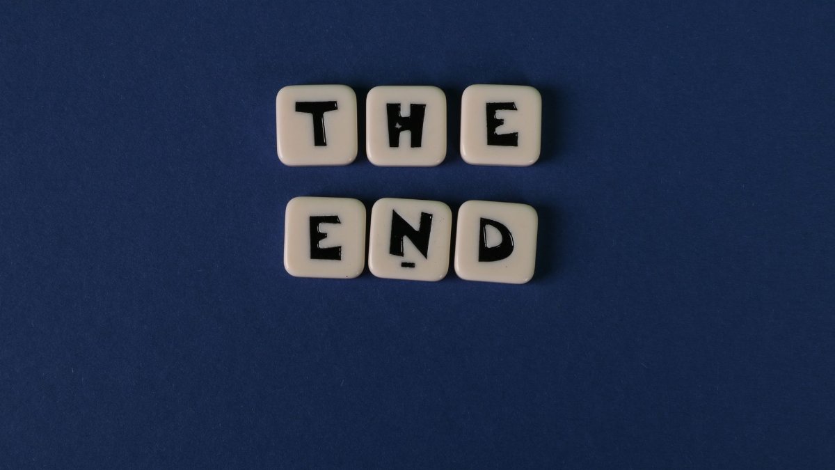 Scrabble tiles spelling 'The End' on a minimalist blue background. Perfect for conceptual designs.