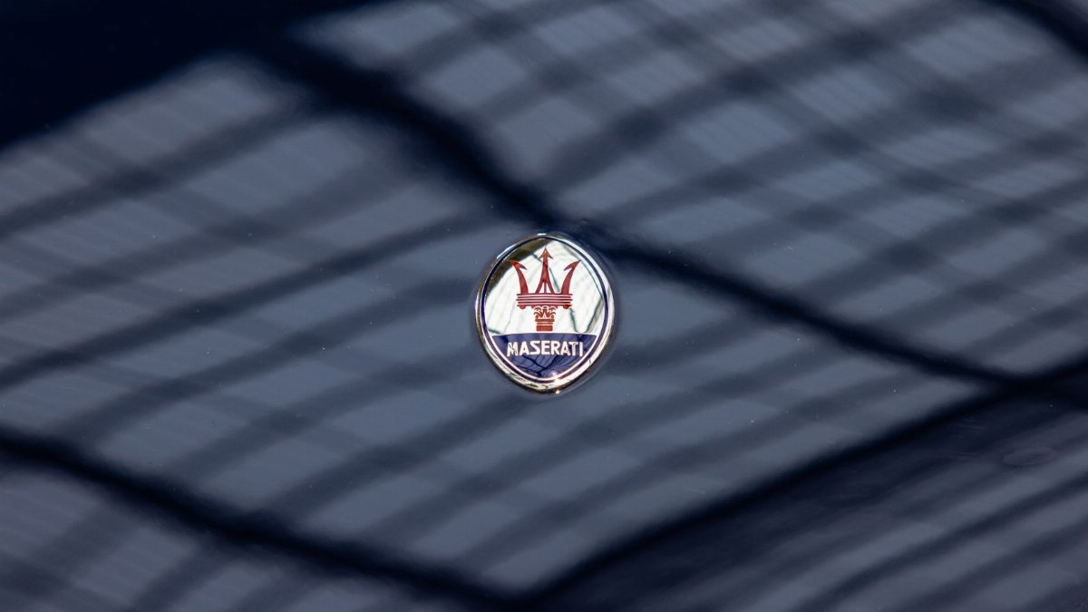 Maserati logo emblem on a dark glossy car surface with reflections, focus on luxury branding.