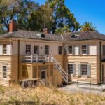 Old mansion at Angel Island State Park with ocean view and natural landscape under clear blue sky.