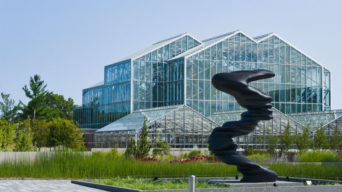 Modern architectural greenhouse in Grand Rapids, MI park with sculpture.
