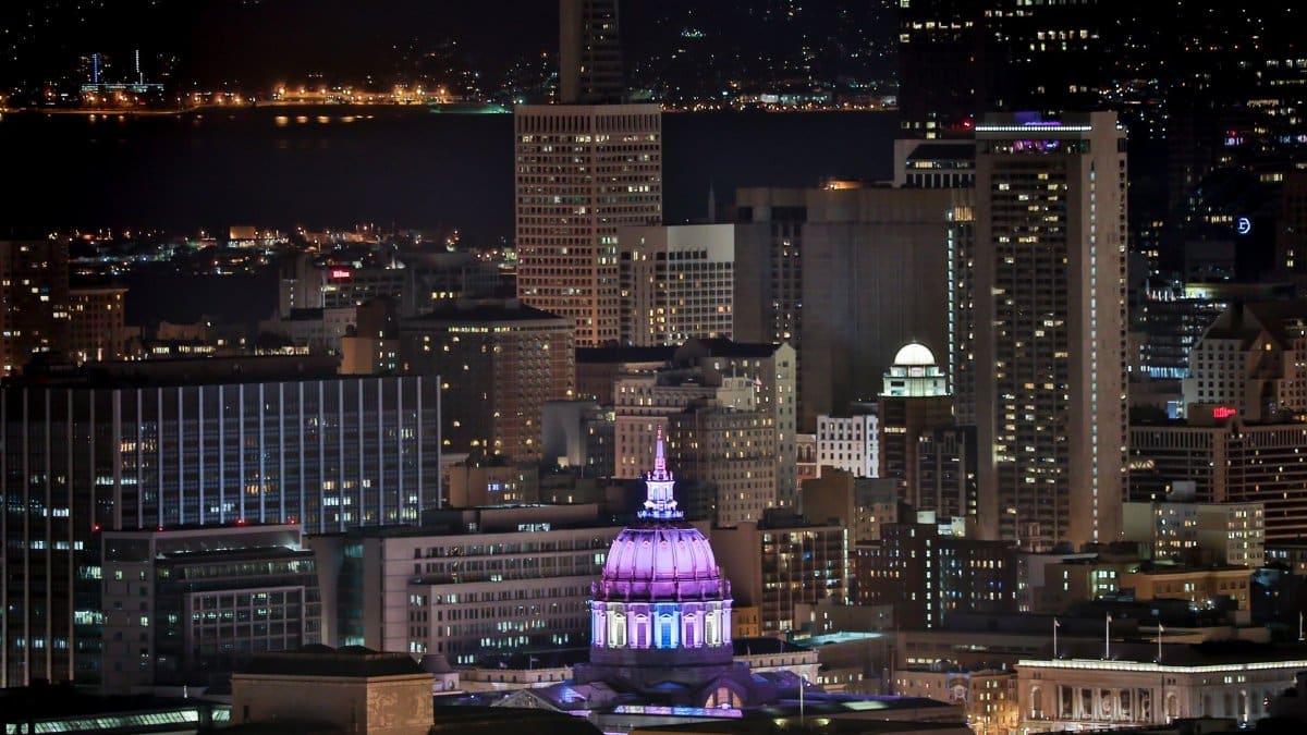 A stunning view of San Francisco skyline at night, featuring a brightly lit dome.
