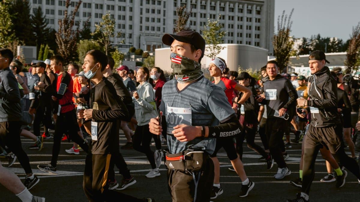 A vibrant marathon in an urban setting with runners wearing face masks and activewear.