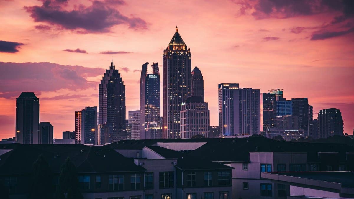 The Atlanta skyline under a picturesque pink sunset, featuring high-rise skyscrapers.