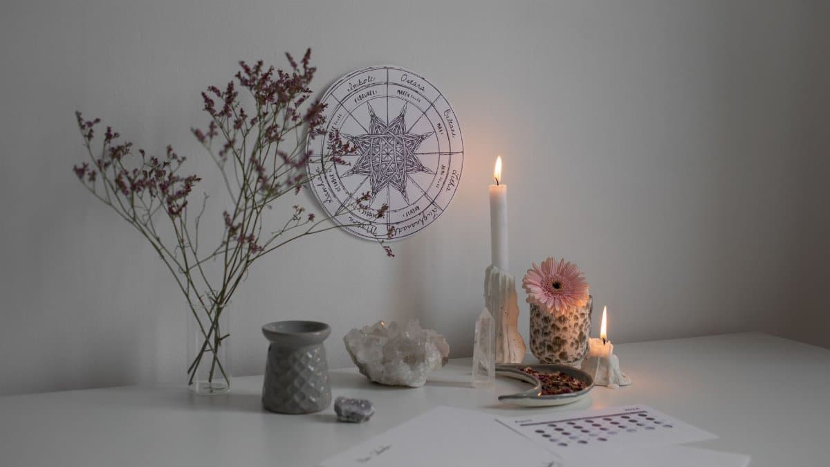 A serene desk setup with candles, crystals, and a wheel of the year decoration.