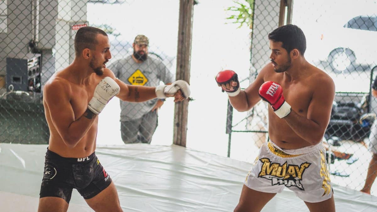 Two men practicing mixed martial arts in a gym, showcasing combat skills.