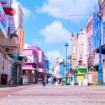 Vibrant downtown street in Bridgetown, Barbados with colorful buildings and a clear blue sky.