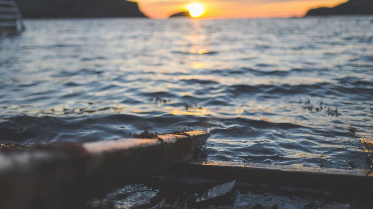 Tranquil seascape with sunset reflecting on gentle ocean waves, creating a peaceful ambiance.