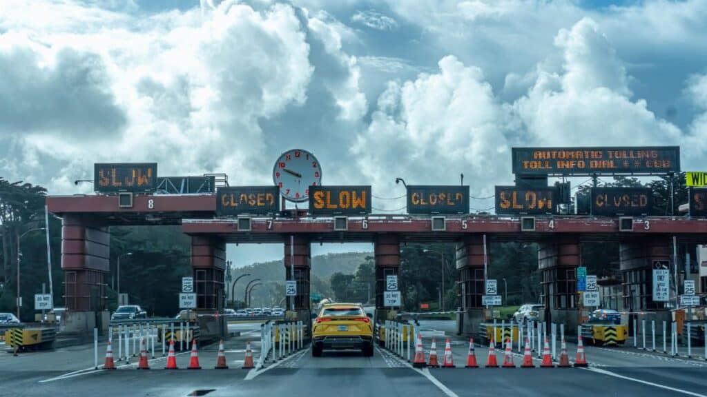 View of vehicles approaching the toll plaza at Golden Gate Bridge in San Francisco under a cloudy sky.