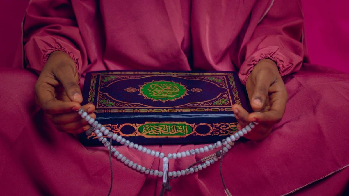 Hands holding Islamic prayer beads and a Quran, emphasizing spirituality and faith.