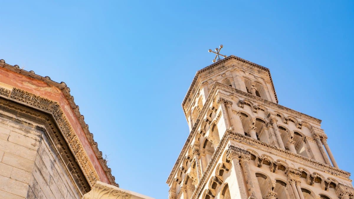 Detailed view of a historic tower in Split, Croatia against a clear blue sky.