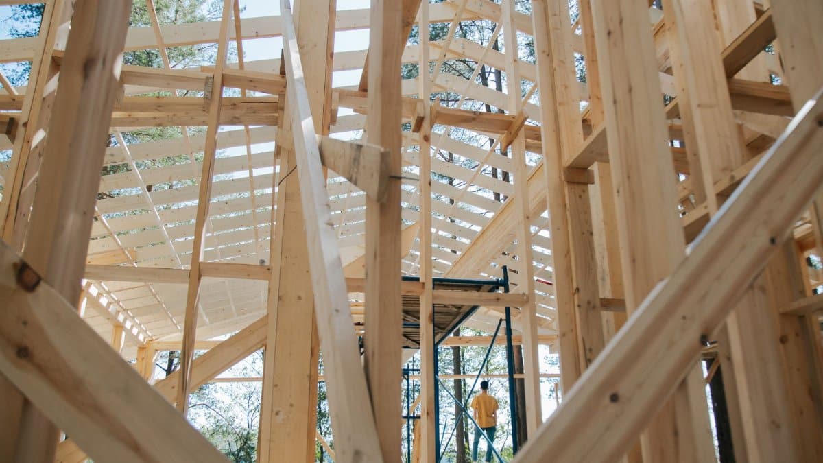 Interior view of wooden house frame under construction with visible scaffolding.