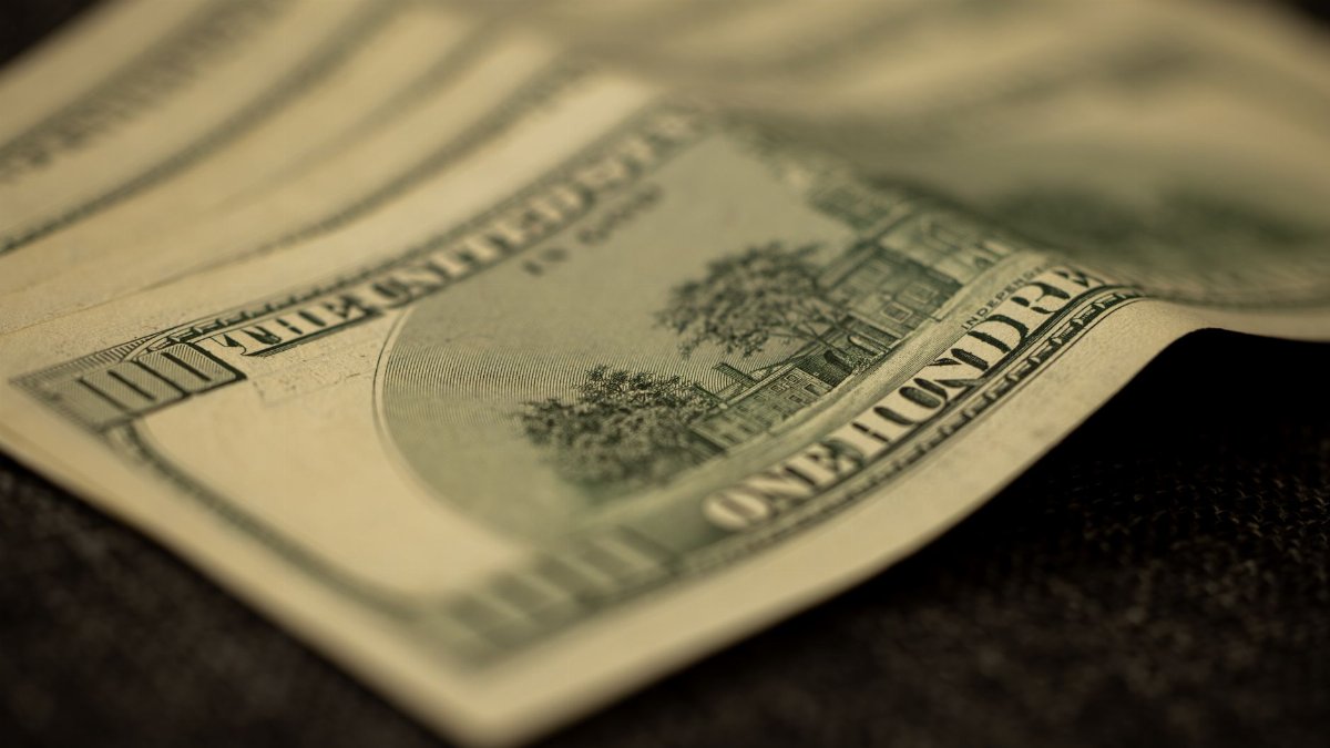 Detailed shot of multiple US hundred dollar bills fanned out on a flat surface, symbolizing wealth.