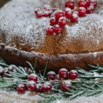 Palatable cake with red berry bunch and powdered sugar near fir sprigs during New Year holiday