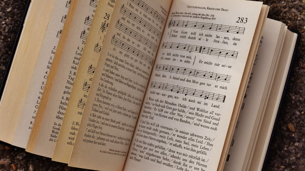 Close-up of an open book displaying musical notes and lyrics on a textured ground surface.