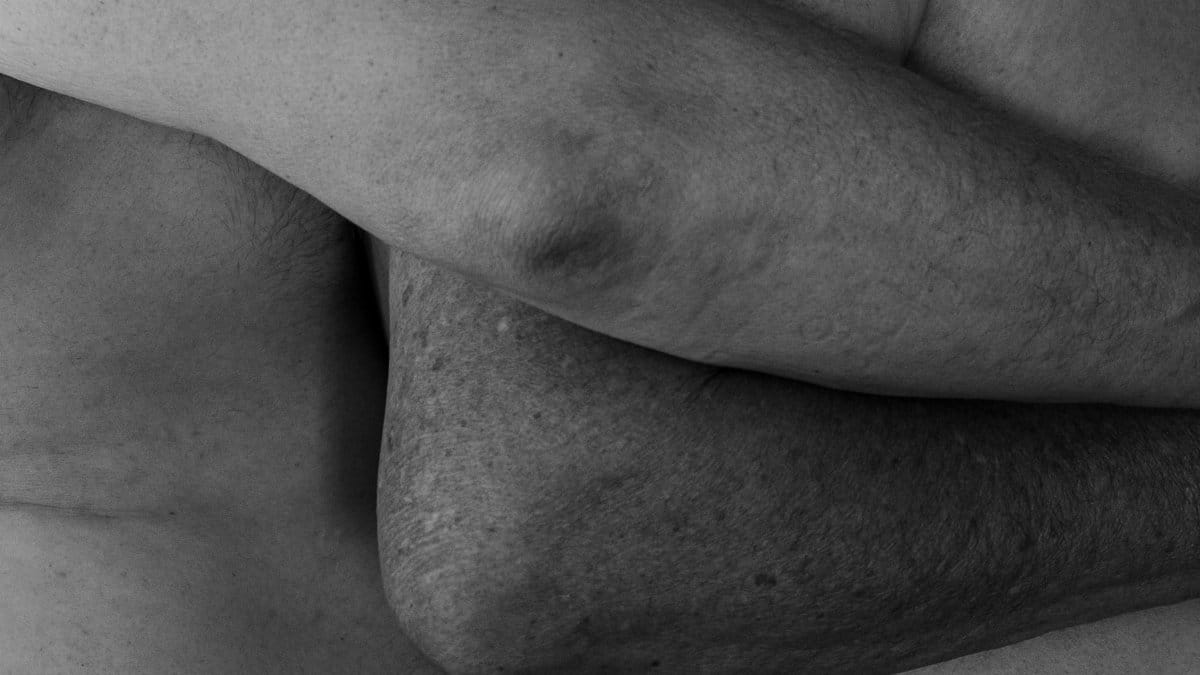 A black and white close-up of intertwined bodies showcasing intimacy and connection.