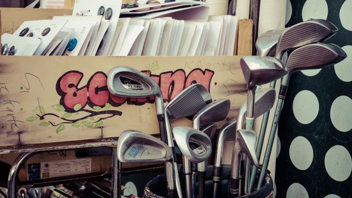 A collection of vintage golf clubs displayed in a flea market setting with retro decor.
