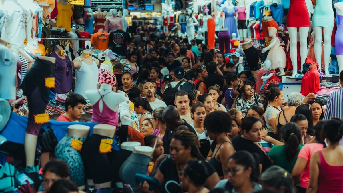 Crowded urban market bustling with people shopping amidst display mannequins.