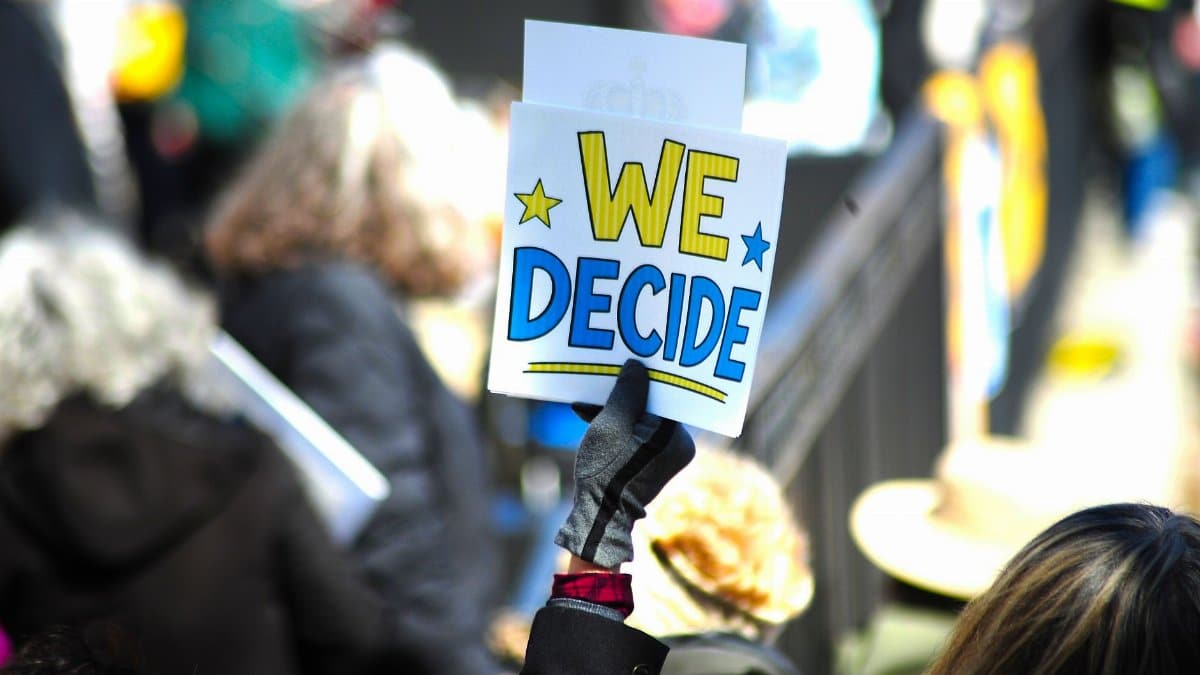 Vibrant protest scene in Baltimore with a sign "We Decide" showcasing civic engagement.