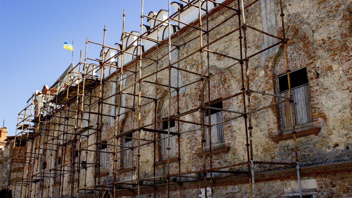 Scaffolding set up on an old brick building under restoration, with a flag above.
