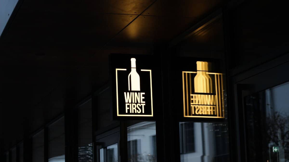 Illuminated 'Wine First' sign in Warsaw, reflecting a cozy nightlife scene.