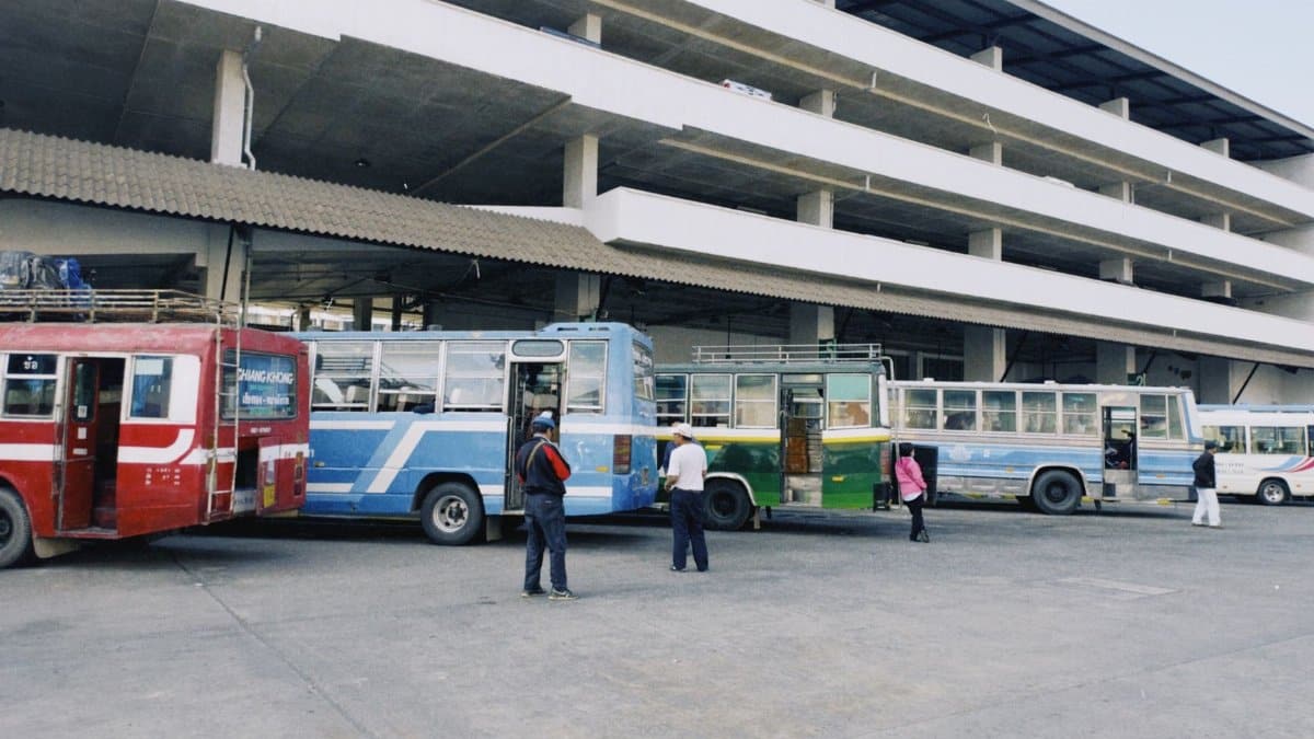 An urban bus station with several colorful buses parked, capturing public transportation in action.