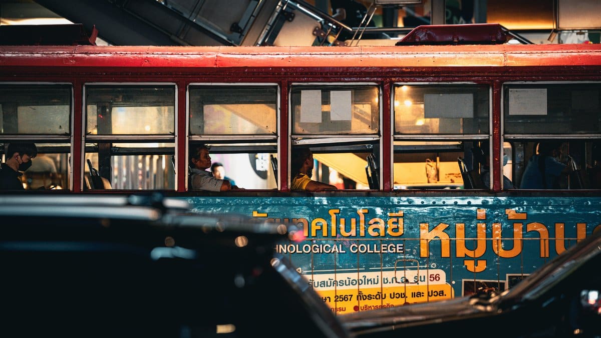 Street view of people inside a Bangkok bus, showcasing urban life and transportation.