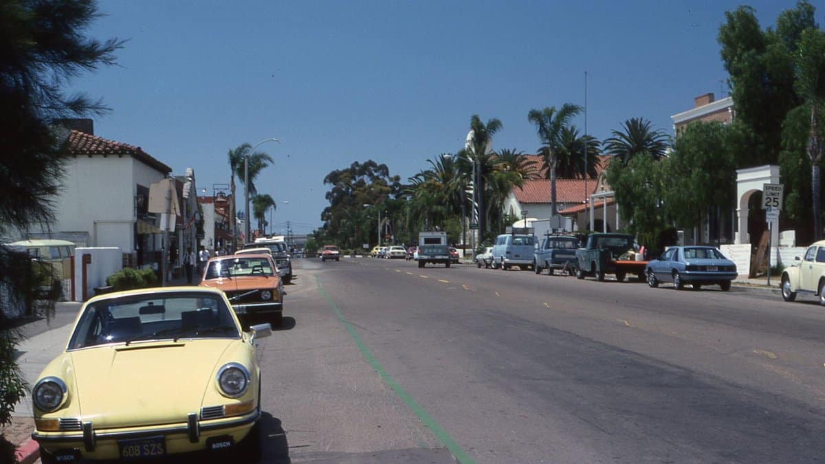 Retro cars line a palm-lined street in a sunny California town.