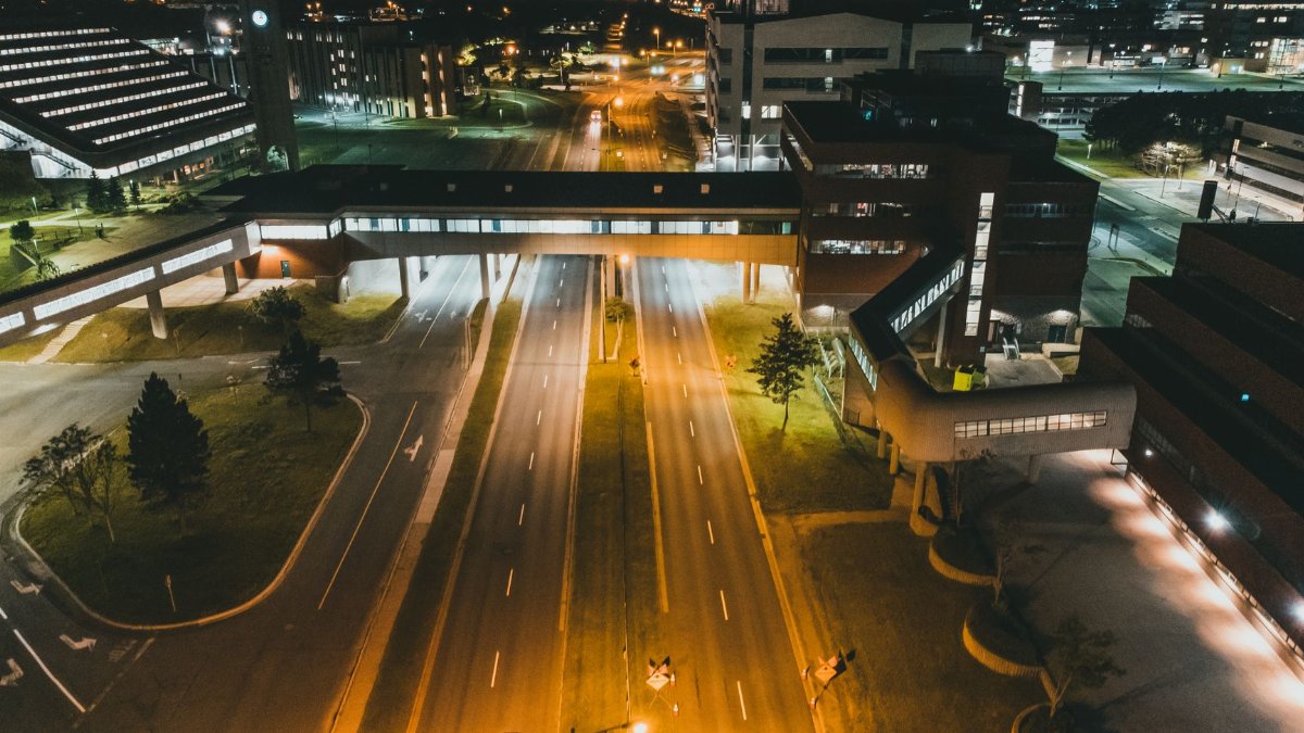 Aerial view of a well-lit urban area at night, showcasing streets, buildings, and city lights.