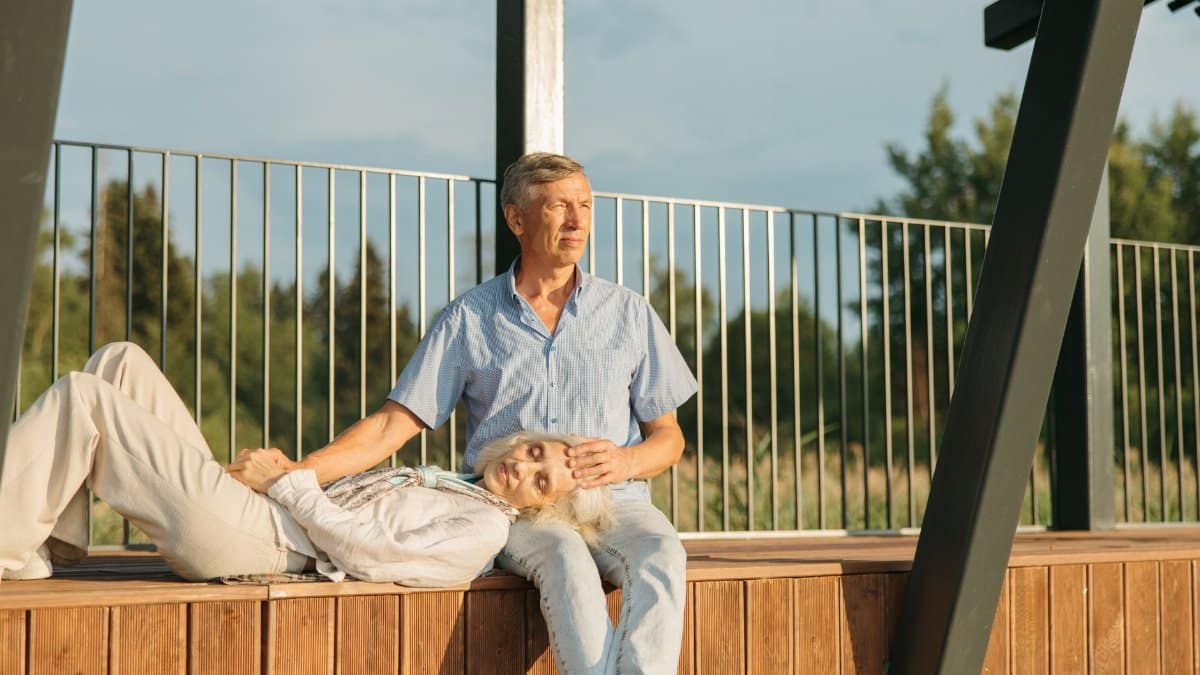 Senior couple resting outdoors on a sunny day, enjoying togetherness.