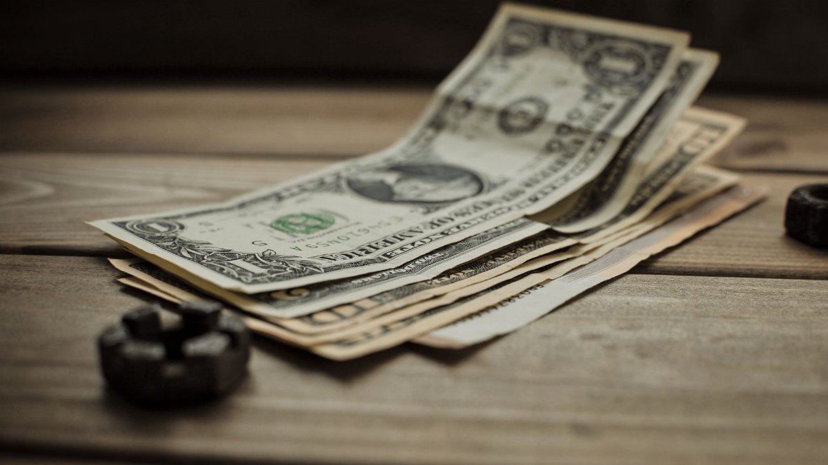 Close-up of US dollar bills on a wooden table, representing finance and commerce.