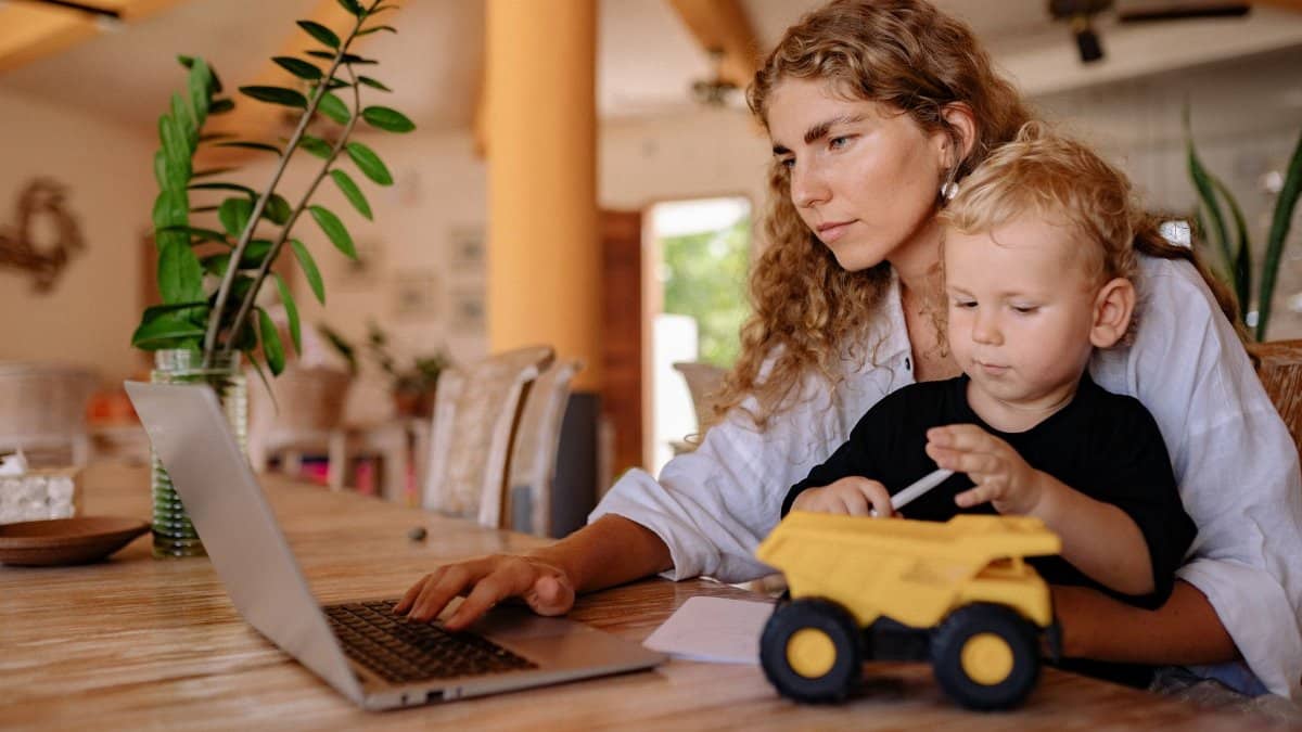 Mother balancing work at home while spending time with her child.