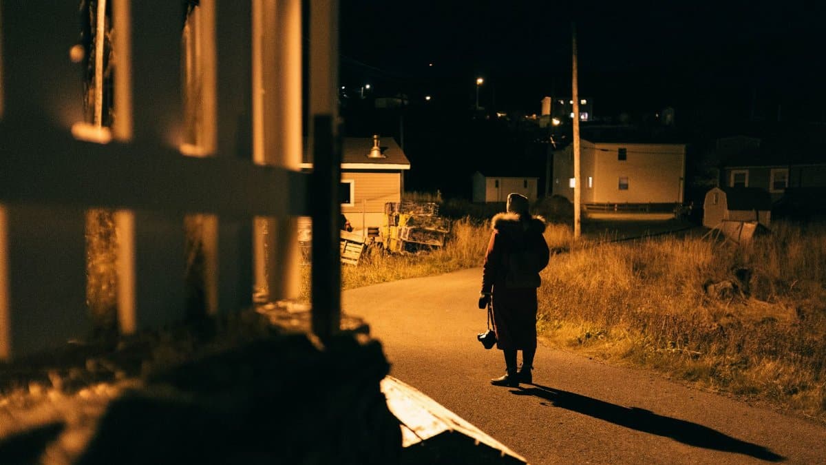 A solitary figure walks through a dimly lit urban area, capturing the essence of night in a small town.