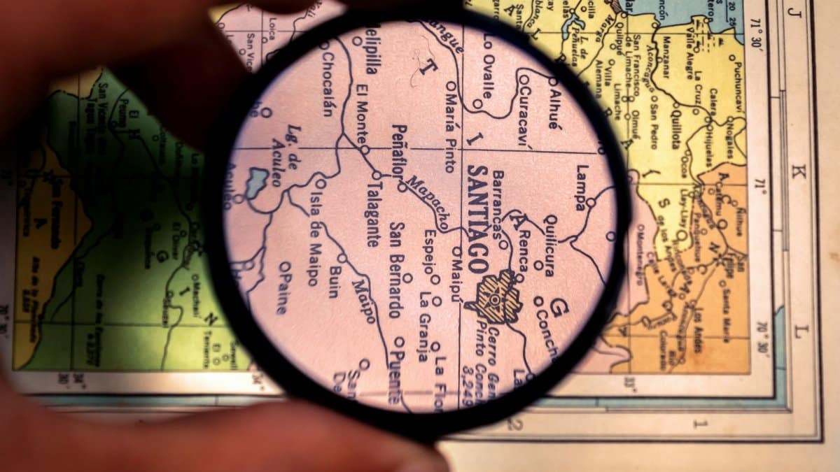 Close-up of a magnifying glass highlighting Santiago on a vintage map of Venezuela.