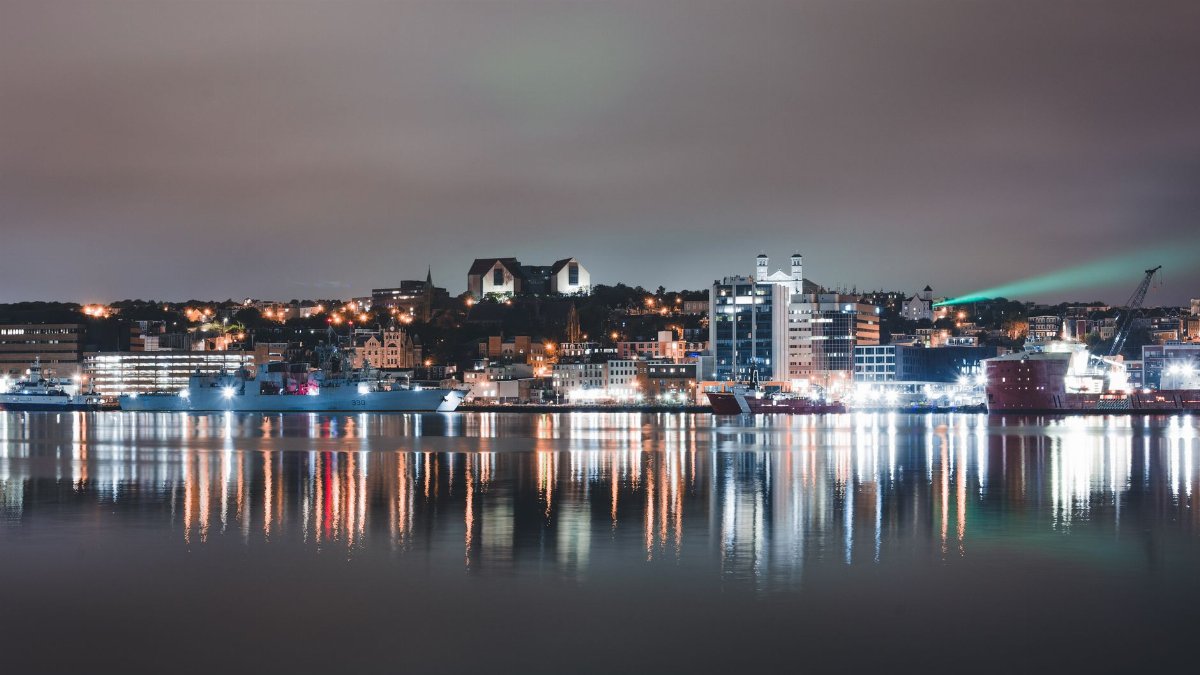A captivating night view of a city harbor with illuminated buildings and reflections on calm water.