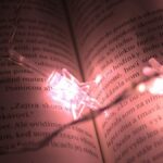 A book page beautifully lit by star-shaped string lights, creating a warm ambiance.