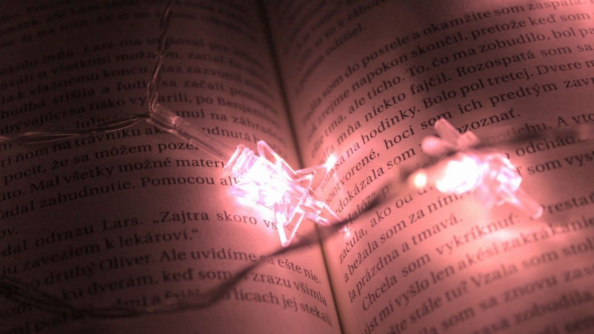 A book page beautifully lit by star-shaped string lights, creating a warm ambiance.