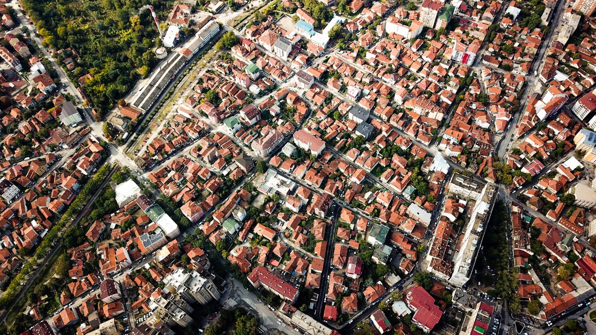 Aerial shot showcasing city blocks with distinct red-roofed buildings and greenery.