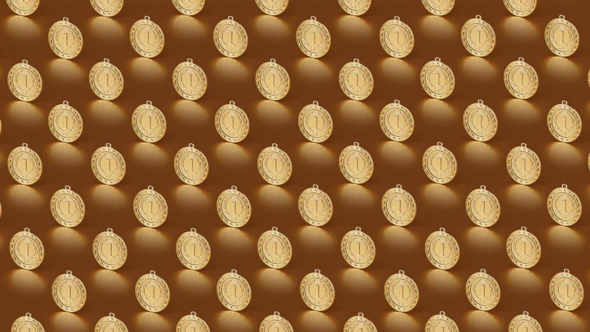 Multiple gold medals arranged in a repeating pattern on a brown backdrop.