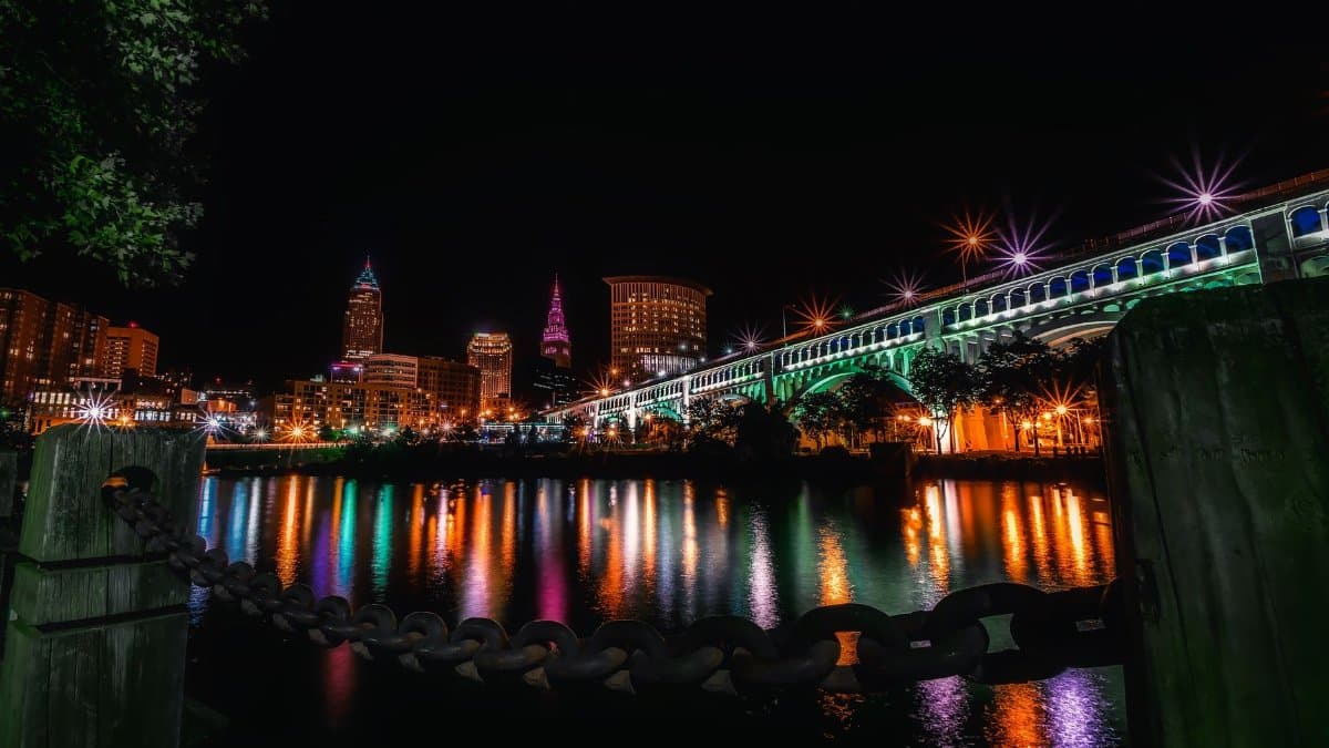 Stunning night view of Cleveland skyline and illuminated bridge reflecting on the river.