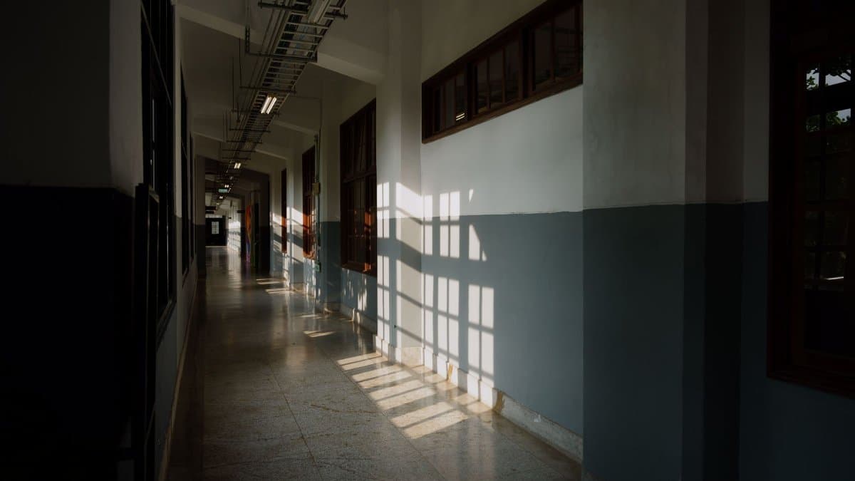 Sunlight casts shadows in an empty corridor of a modern building, creating a serene and contemplative atmosphere.