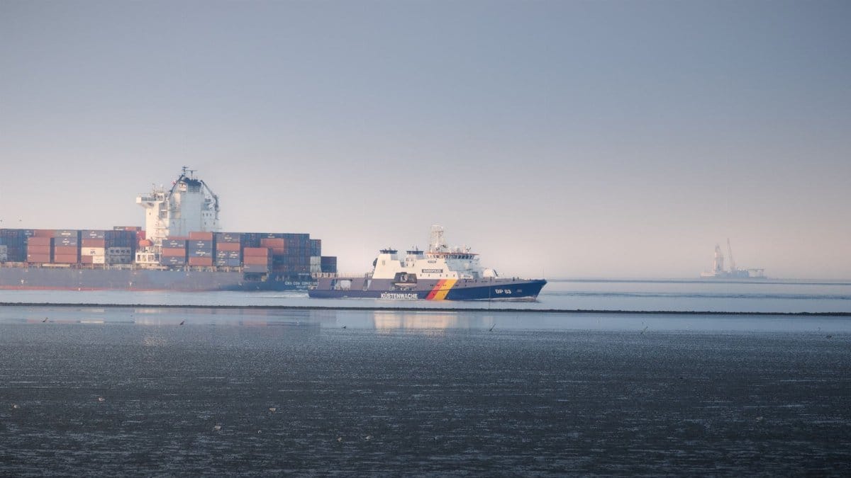 Coast Guard and container ships sailing near Cuxhaven, Germany, under clear skies.