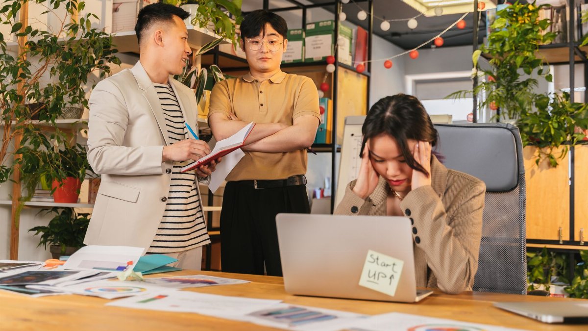 Colleagues engaged in a discussion in a modern office setting with indoor plants and documents.