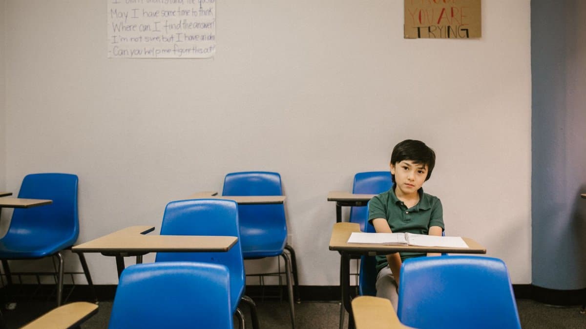 Young boy alone in a classroom, depicting solitude and school challenges.